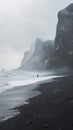 Lone person walking on a misty black sand beach with rugged cliffs