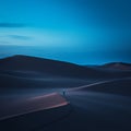 a lone person walking through the sand dunes at dusk Royalty Free Stock Photo