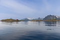 A solitary red Rorbu on Lofoten, Norway, with sea reflecting the clear sky and snowy peaks Royalty Free Stock Photo