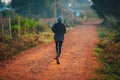 A lone runner trains in Kenya. A marathon runner runs on red soil in the city of Iten, home of Champions. Motivation to run,