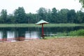 A lone, sagging sunken umbrella and fencing, a playpen for bathing children on a sandy beach on the shore of a lake, a river at a Royalty Free Stock Photo