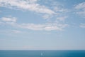 A lone sailboat floats in the distance on calm water against a background of blue sky. The concept of freedom and ease Royalty Free Stock Photo