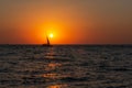 A lone sailboat at sunset. Atmospheric seascape with orange sun Royalty Free Stock Photo