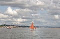 Starcross, devon: sailing boat with dark orange sails, clouds