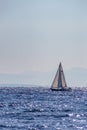 A lone sailing boat sails in the shimmering sea around the island of Zakynthos, Greece