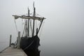 A lone ship is tethered to the dock on a foggy day