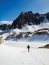 a lone skier trekking through snowy terrain with mountains in the background