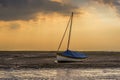 A lone small boat beached at Morston Creek, Norfolk at low tide just before sunset