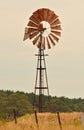 A lone Southern Cross windmill used in irrigation stands in a paddock on a farm.