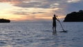 Lone surfer sailing on tropical island Guam at sunset