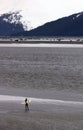 Lone Surfer Stands On Muddy Beach Waiting For A Wave In Alaska