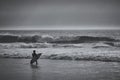 Lone surfer walks into the ocean to catch a wave. Portugal.