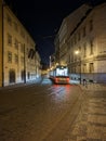 A lone tram gliding through the city of Prague, its lights painting streaks in the night