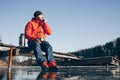 A lone tramp traveler stands on ice and drinks tea from a thermos