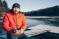 A lone tramp traveler stands on ice and drinks tea from a thermos