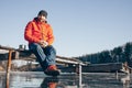 A lone tramp traveler stands on ice and drinks tea from a thermos.