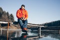 A lone tramp traveler stands on ice and drinks tea from a thermos.