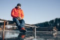 A lone tramp traveler stands on ice and drinks tea from a thermos.