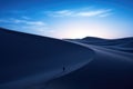Lone traveler in a desolate landscape amidst swirling sand dunes