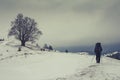 Lone traveler walking along the road in the mountains. Winter landscape.