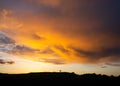 Lone tree standing on hill silhouette with dramatic orange sky sunset storm above Royalty Free Stock Photo