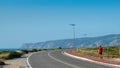 Lone unidentifiable walker or runner on sidewalk at Praia do Guincho heading towards Cabo da Roca near Sintra, Portugal