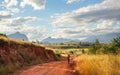 Lone unknown young Malagasy man with basket on his shoulders walking over red dusty road, coming home after working the fields,