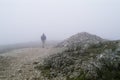 Lone walker in mist by mountain cairn