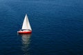 A lone white sail on a calm blue sea