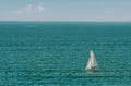 A lone white sail sailboat on a calm blue sea Royalty Free Stock Photo