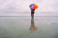 Lone woman at the beach with colorful umbrella