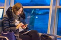 A lone woman in the evening at the airport by the window waiting for a landing on the plane