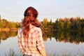 a lone young woman in sunset color stands by the water.selective focus