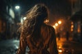 Lone young woman walks away down dark city street in rain, back view. Scared girl with long hair at night alone. Female person