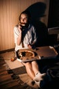 Loneliness in Christmas holidays, Valentines day. Young alone woman in pajamas eating pizza near fireplace at dark home.
