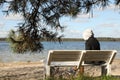 Loneliness concept. Sad man sitting on bench at riverside, selective focus Royalty Free Stock Photo