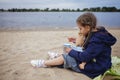 Lonely adorable eight years girl playing with doll on the autumn beach, mother and daughter game