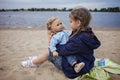 Lonely adorable eight years girl playing with doll on the autumn beach, mother and daughter game