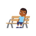 Lonely African boy is bored. Sad little Dark skin kid. Unhappy child sitting on bench.