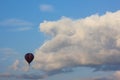 Lonely air baloon flying in front of white puffy clouds