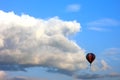 Lonely air baloon flying in front of white puffy clouds against