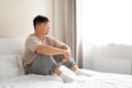 Lonely asian middle aged man wearing pajamas sitting on bed Royalty Free Stock Photo