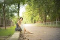 Lonely asian woman teenage in casual dress sit by walkway with big smile hand hold umbrella in public park and copy space. process