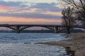 Lonely bare tree on the bank of the Dnieper River. Metro subway Bridge at the background. Winter sunset landscape photo Royalty Free Stock Photo