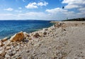 Lonely beach of coarse gravel on the coast of Dalmatia, Croatia with the shilouette of a griffin bird in the cloudy sky