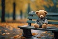 Lonely bear in a plaid shirt on a park bench in a rainy park.