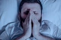 A lonely bearded man in bed at night covered his face before sneezing. Dust in the house, allergy from washing powder, bedroom, Royalty Free Stock Photo