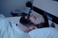 A lonely bearded man sleeps at night with his mouth open, snoring. Apnea syndrome, bedroom, pajamas, white bedding Royalty Free Stock Photo