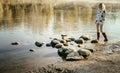 Lonely beautiful girl walks on river bank early in morning