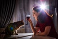 Lonely beautiful middle aged woman alone in the dark kitchen drinking red wine in the evening with her cat Royalty Free Stock Photo